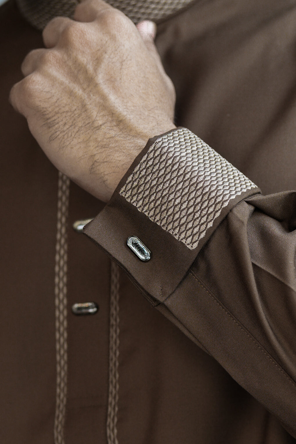 Close-up of a brown jacket with textured cuff and button details