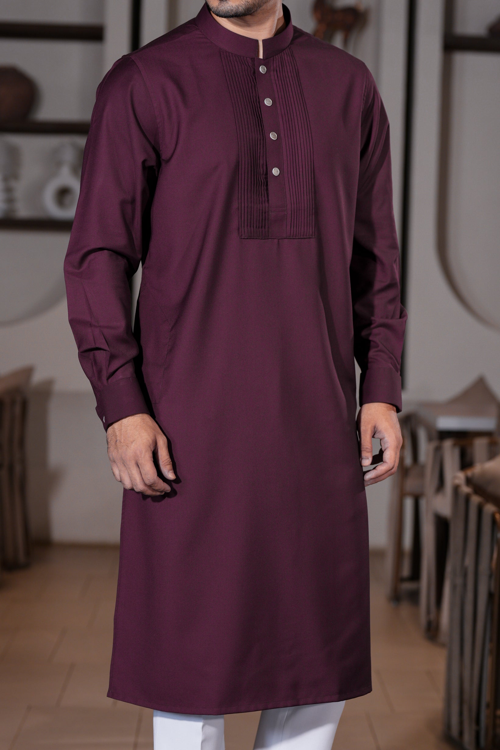 Man wearing a maroon kurta with white pants in an indoor setting