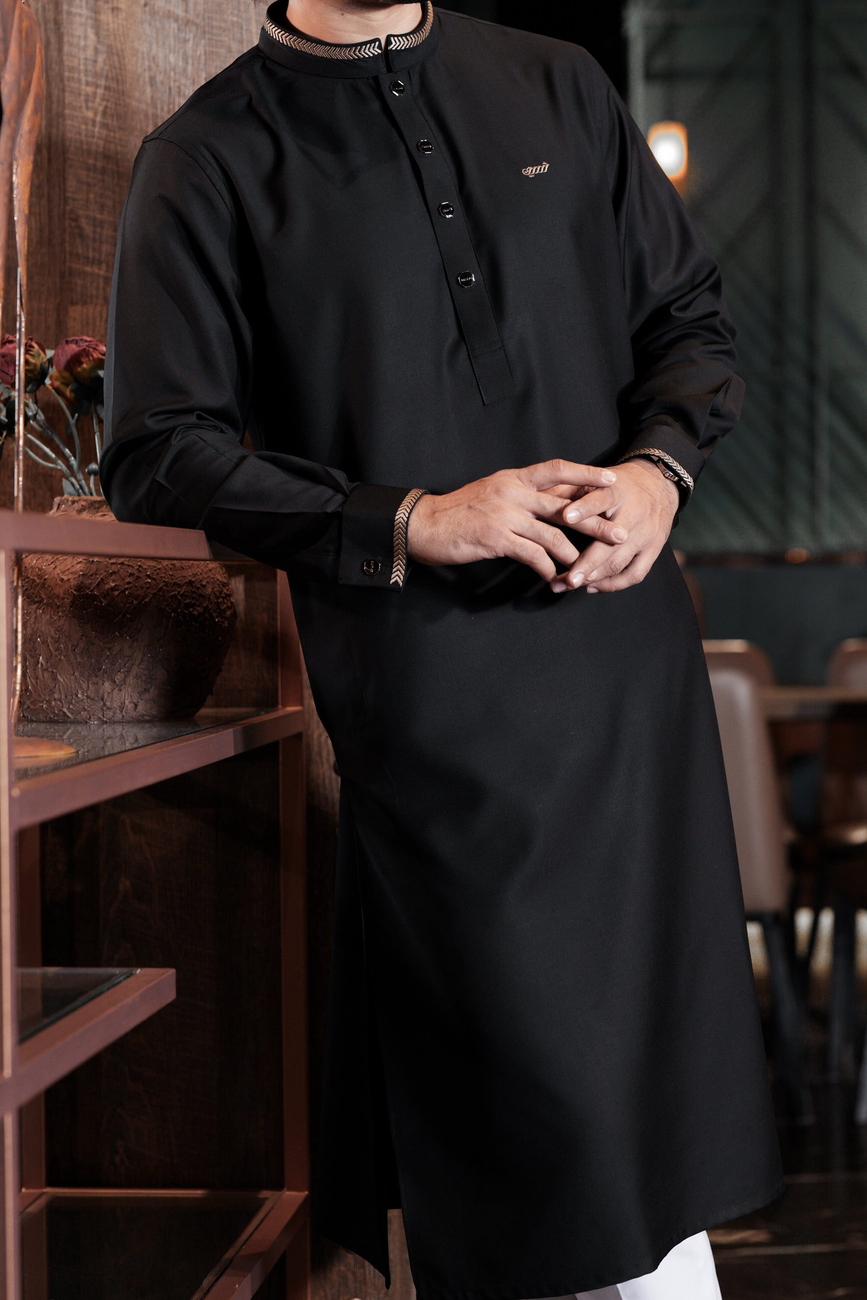 Person wearing a black traditional outfit in an indoor setting