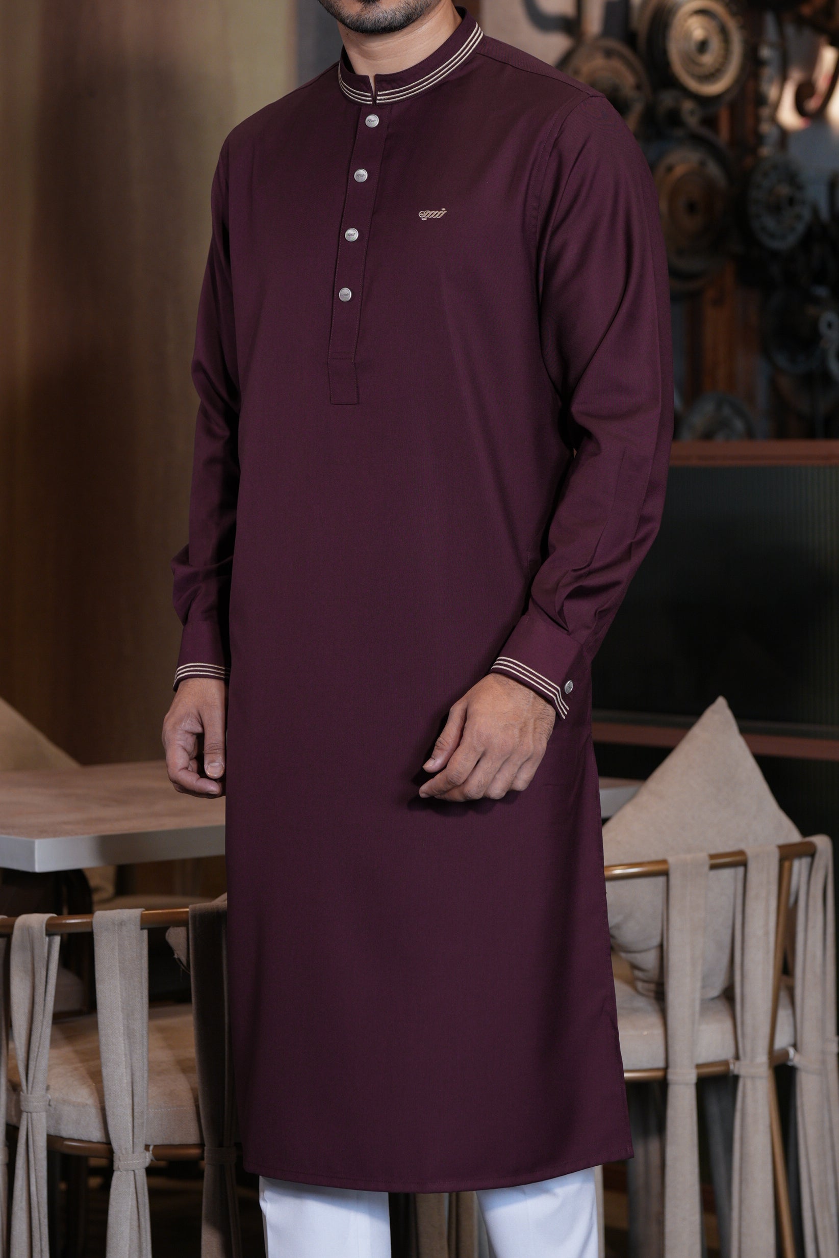 Man wearing a maroon long-sleeve shirt with white buttons in an indoor setting.