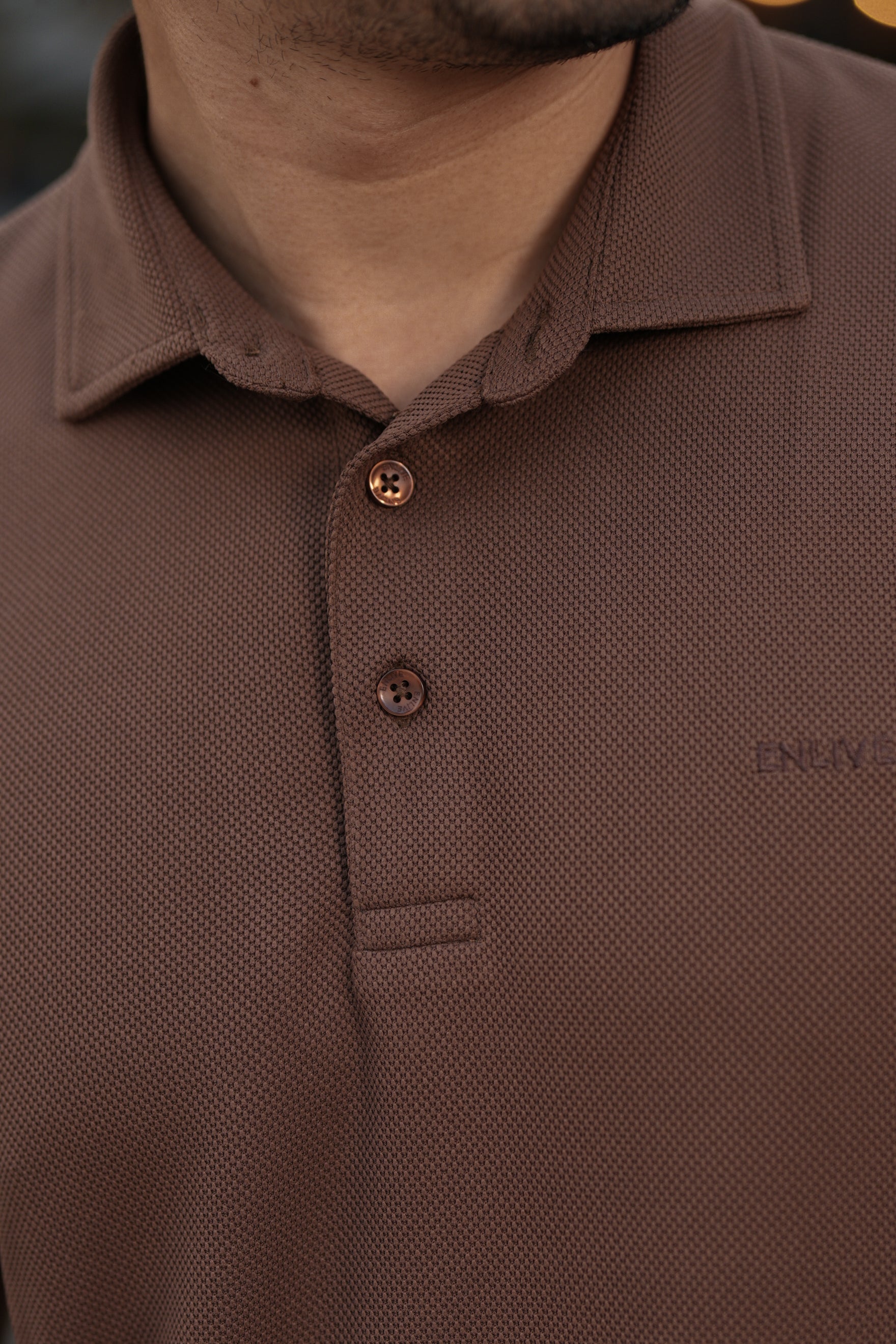 Close-up of a brown polo shirt with visible branding