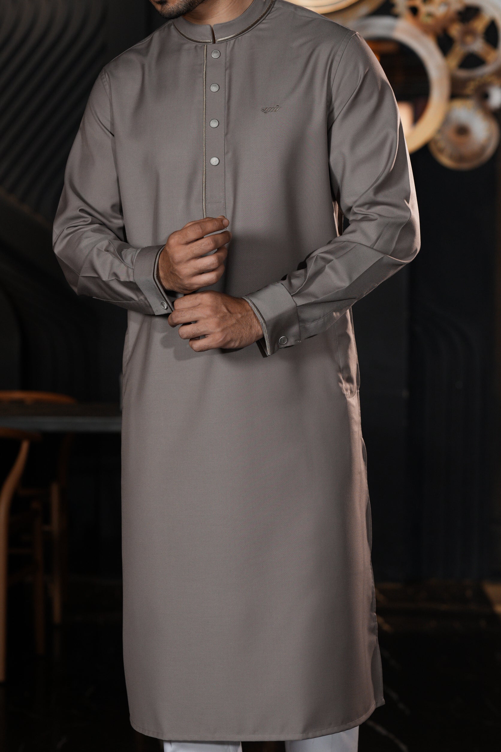 Man wearing a long gray shirt with a blurred background