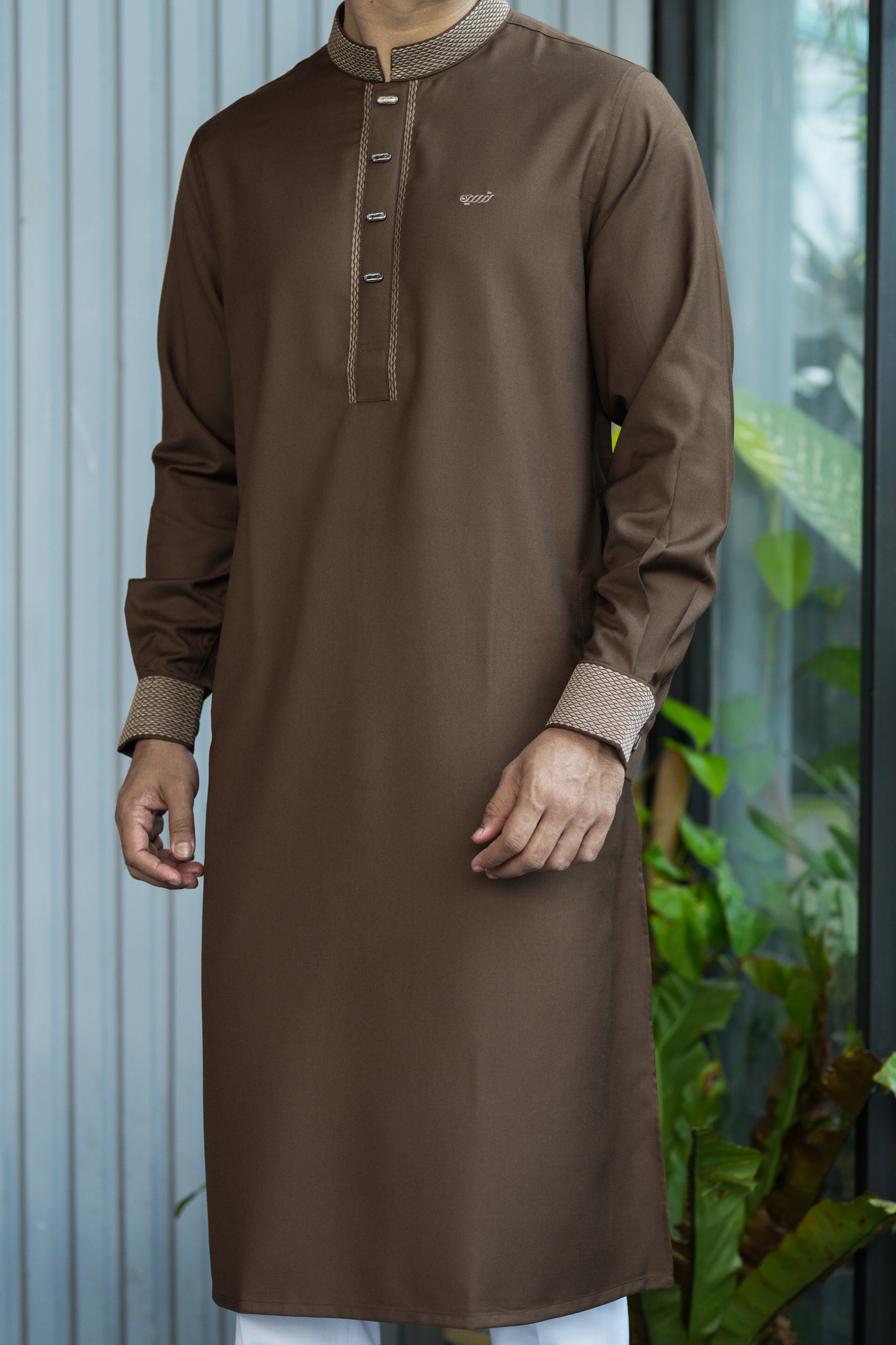 Man wearing a brown traditional outfit with a blurred background