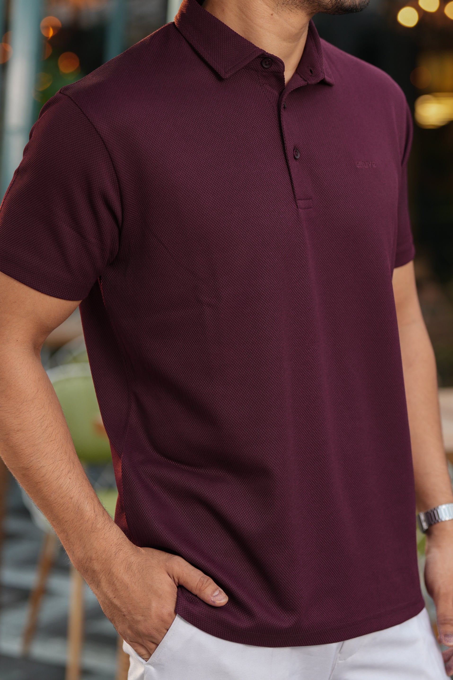 Man wearing a maroon polo shirt with a blurred background