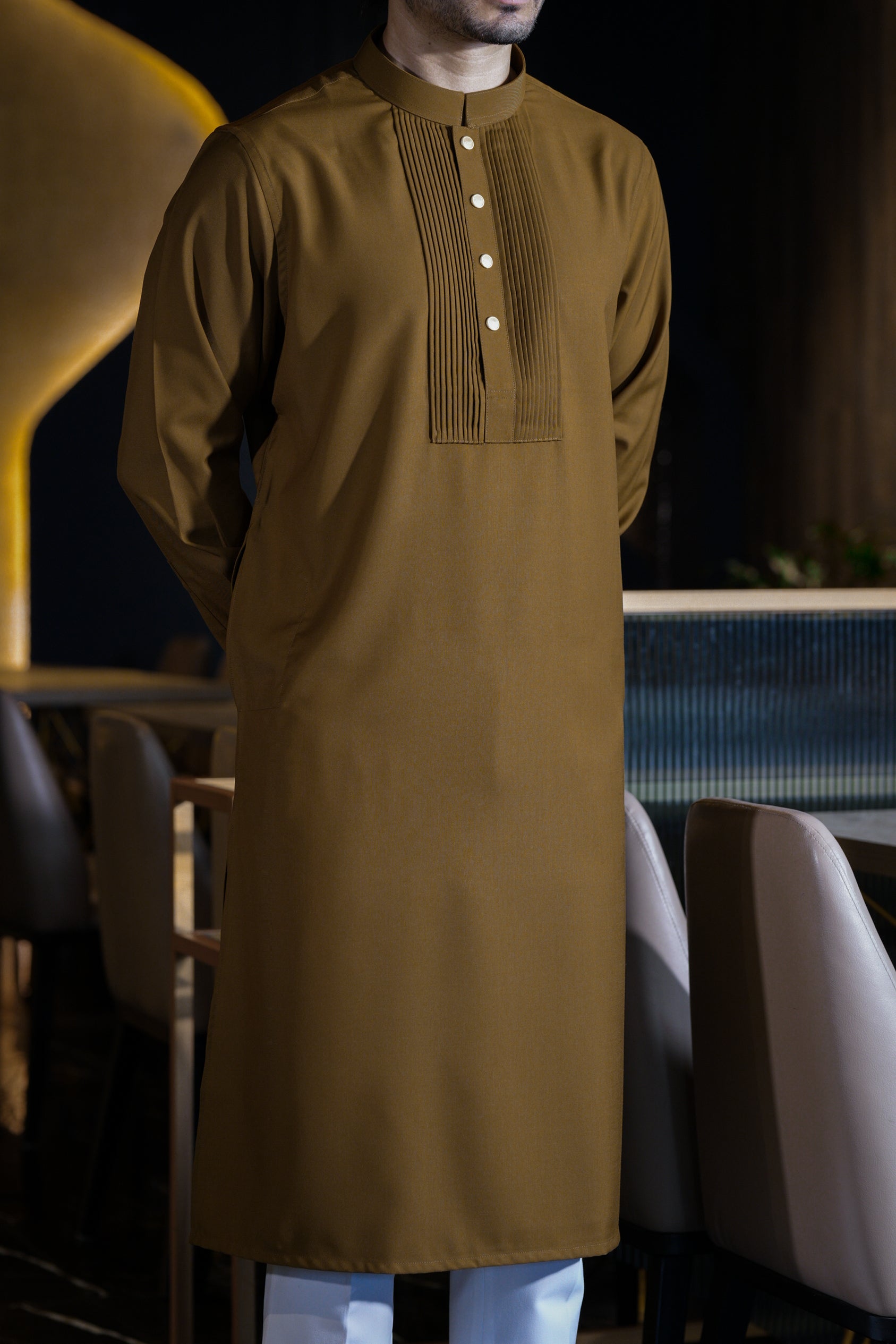 Man wearing a brown traditional outfit in an indoor setting