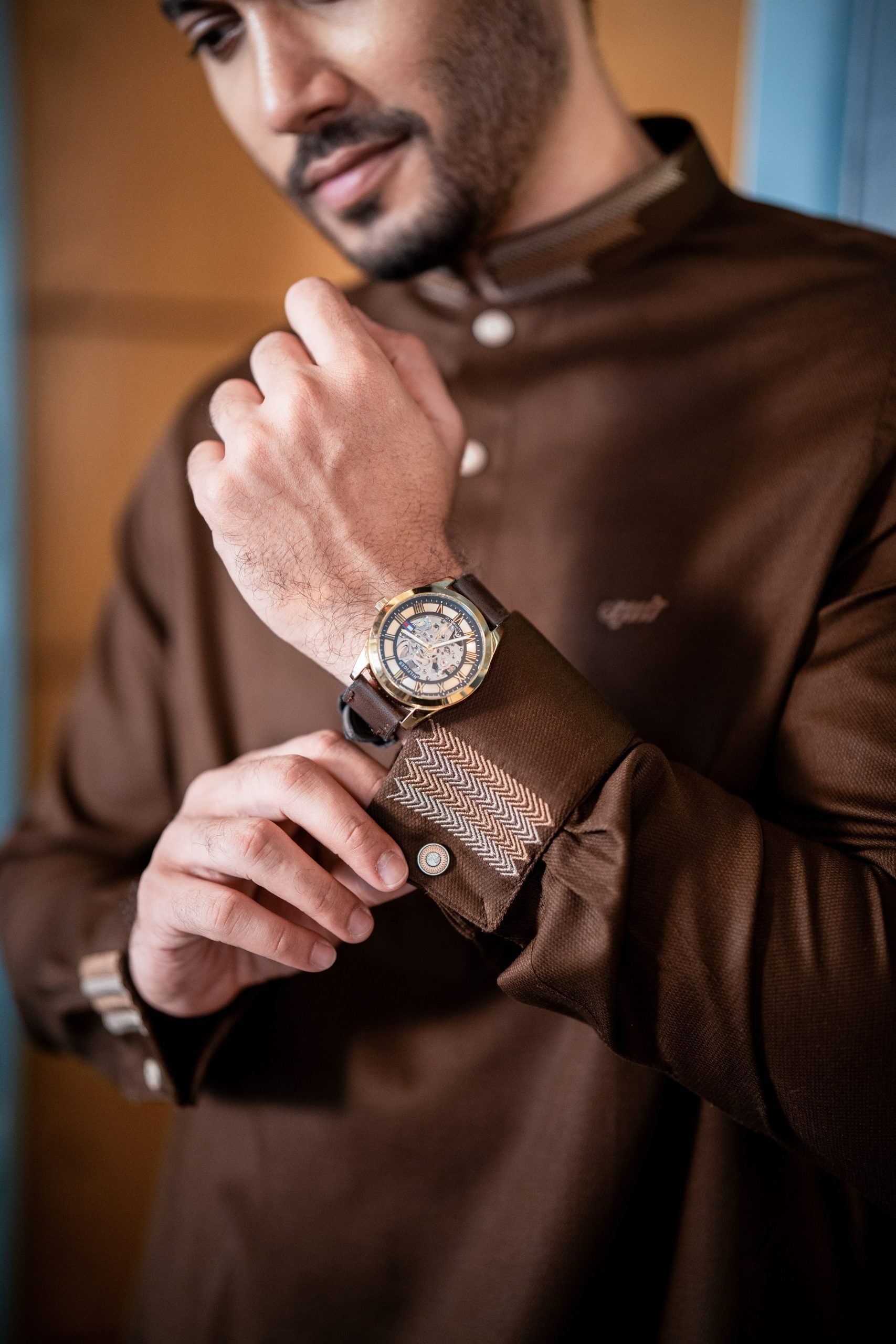 Man adjusting his wristwatch with a close-up of the watch face.