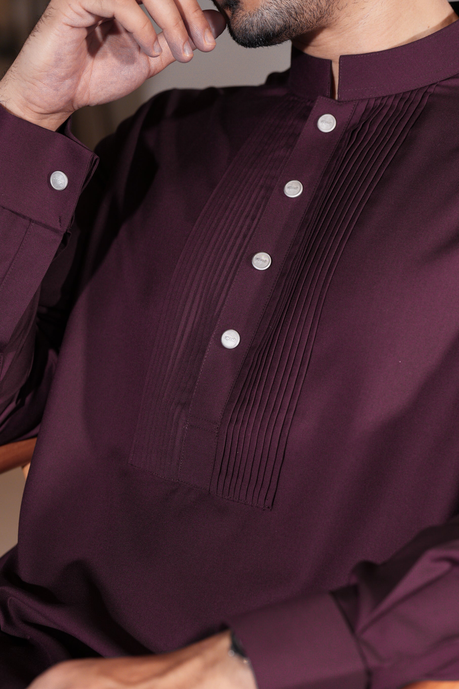 Close-up of a person wearing a dark purple shirt with white buttons.