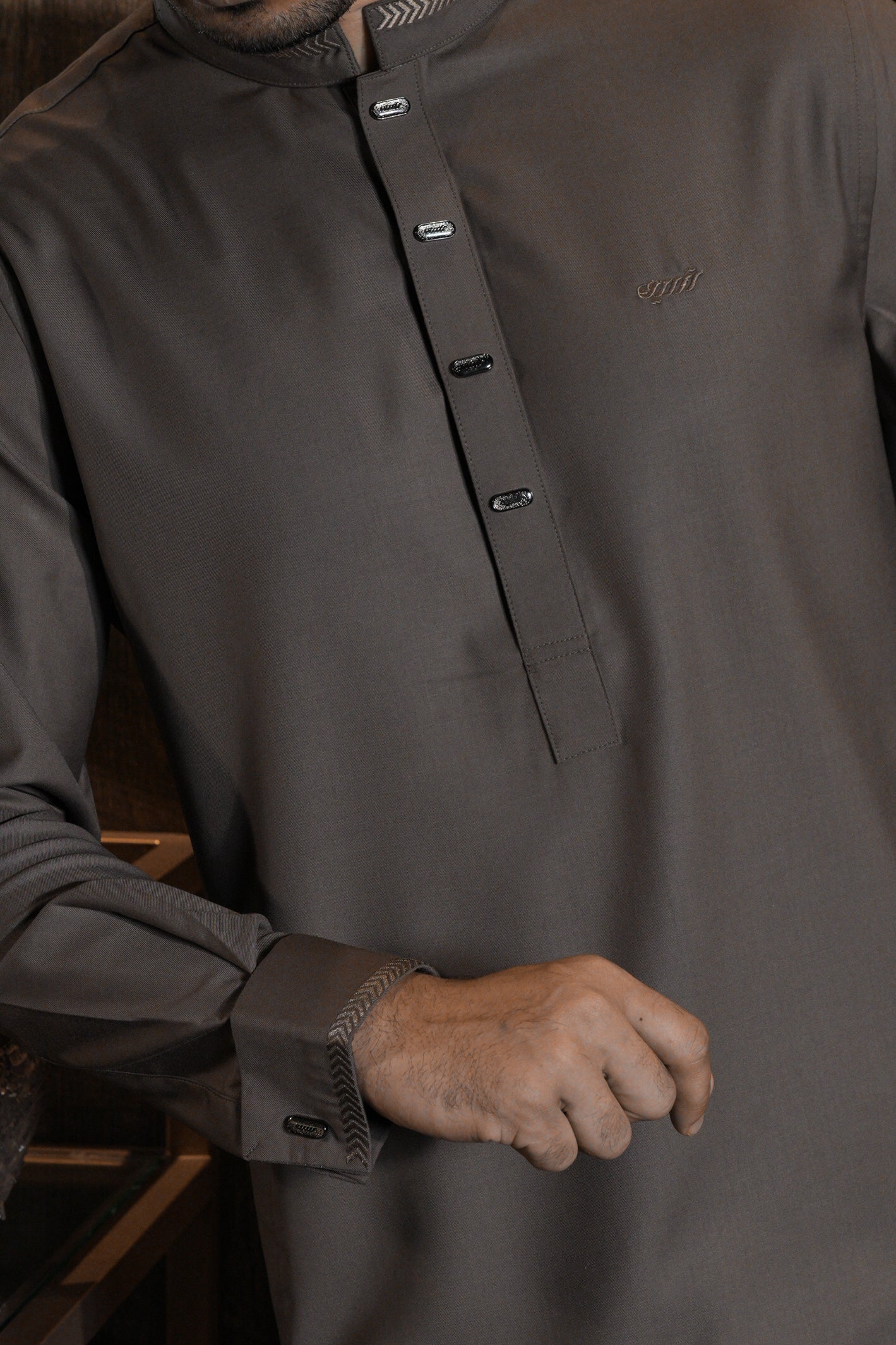 Close-up of a person wearing a dark gray long-sleeve shirt with a collar and button details.