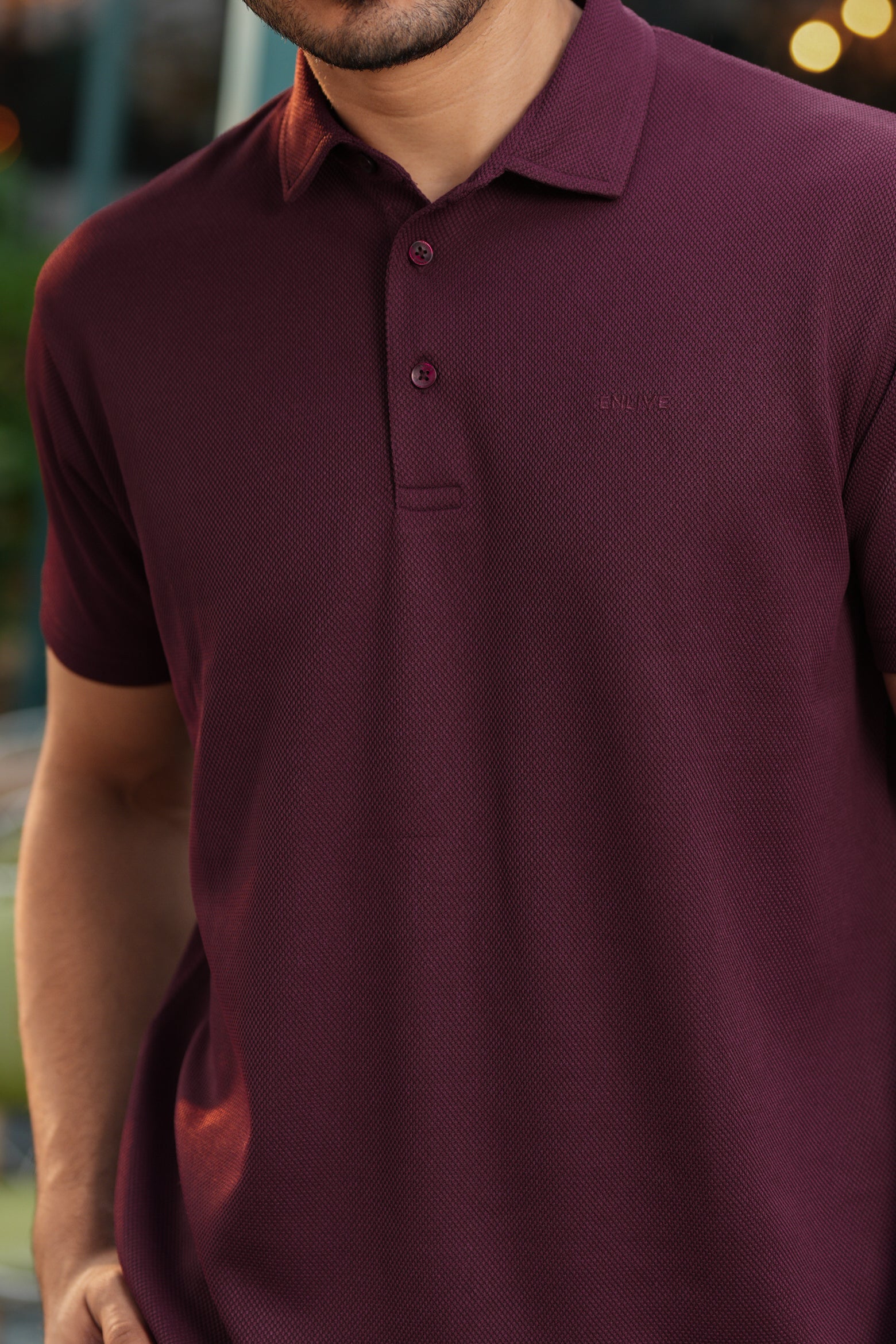 Man wearing a maroon polo shirt with a blurred background