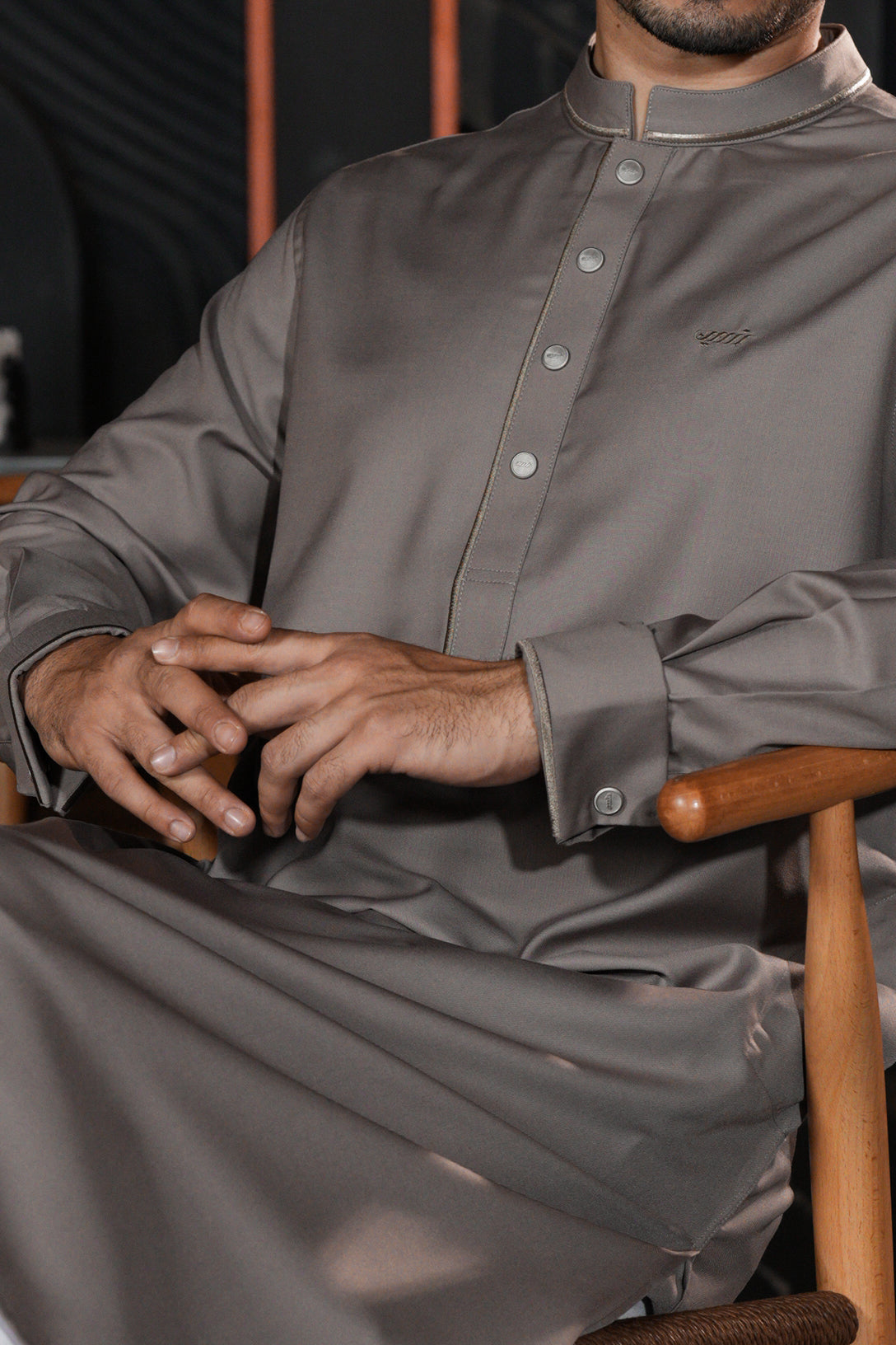 Person wearing a gray long-sleeve shirt sitting on a wooden chair.