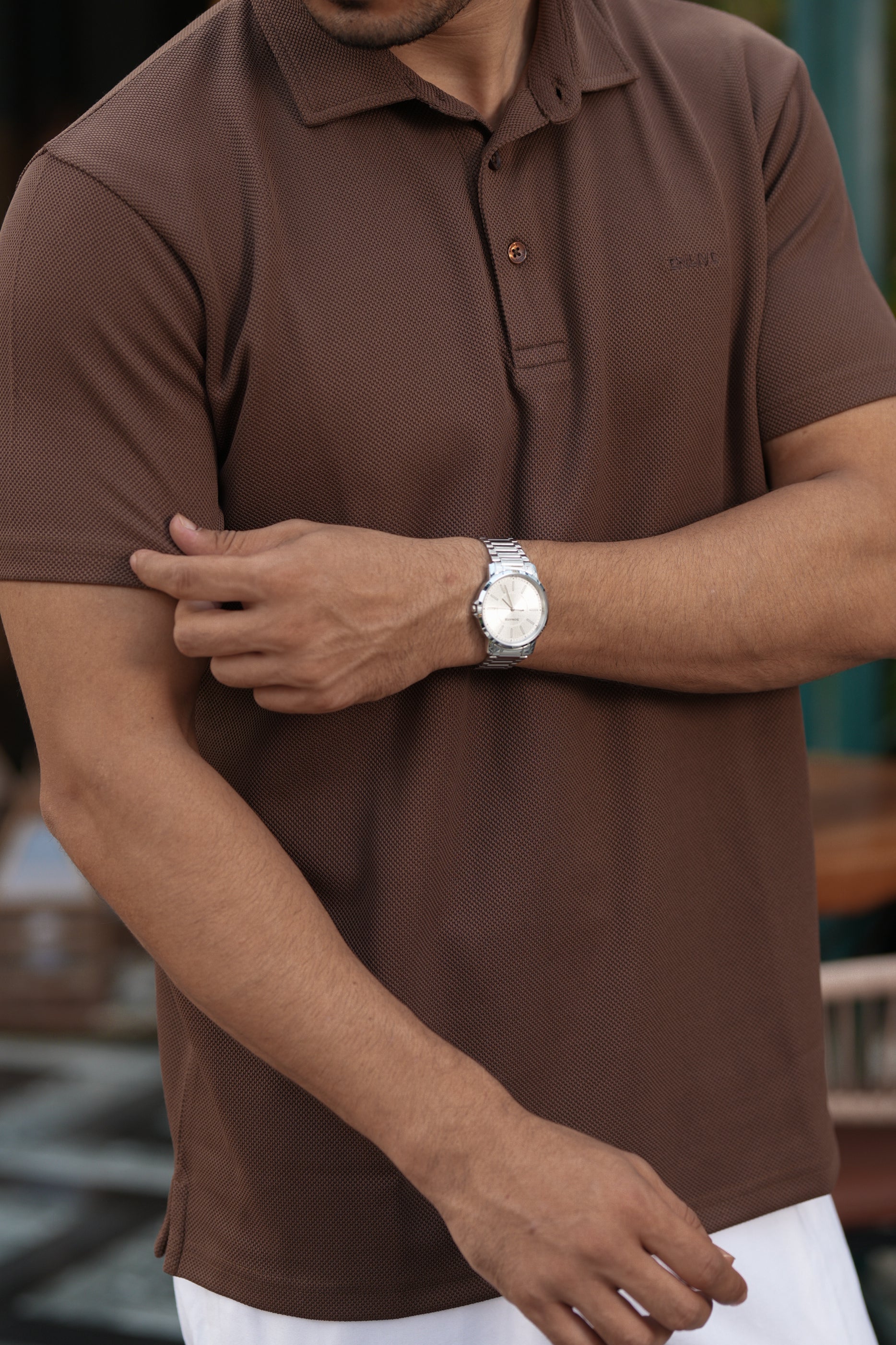Man wearing a brown polo shirt with a blurred background