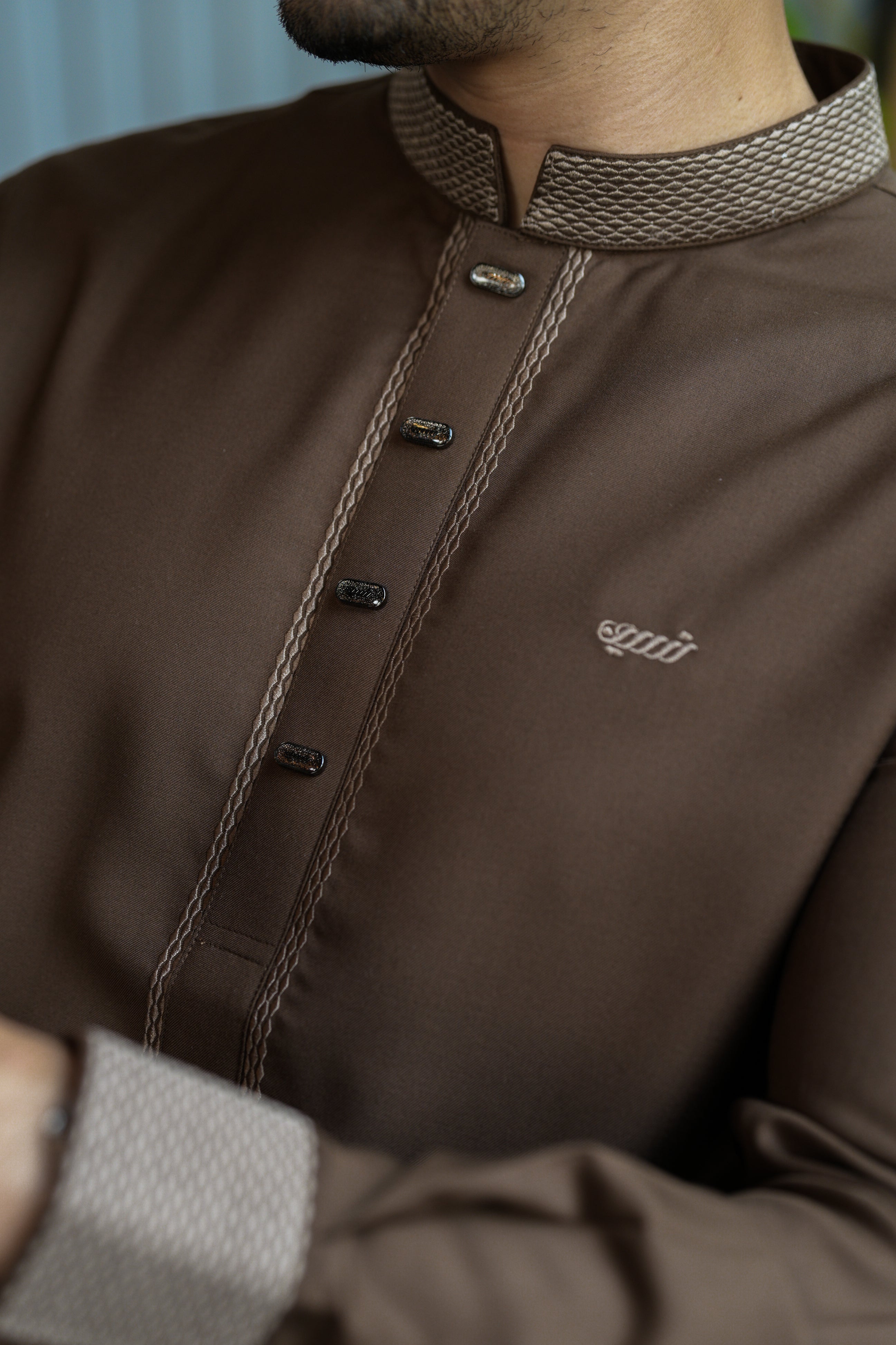 Brown shirt with textured collar and brand logo on a blurred background