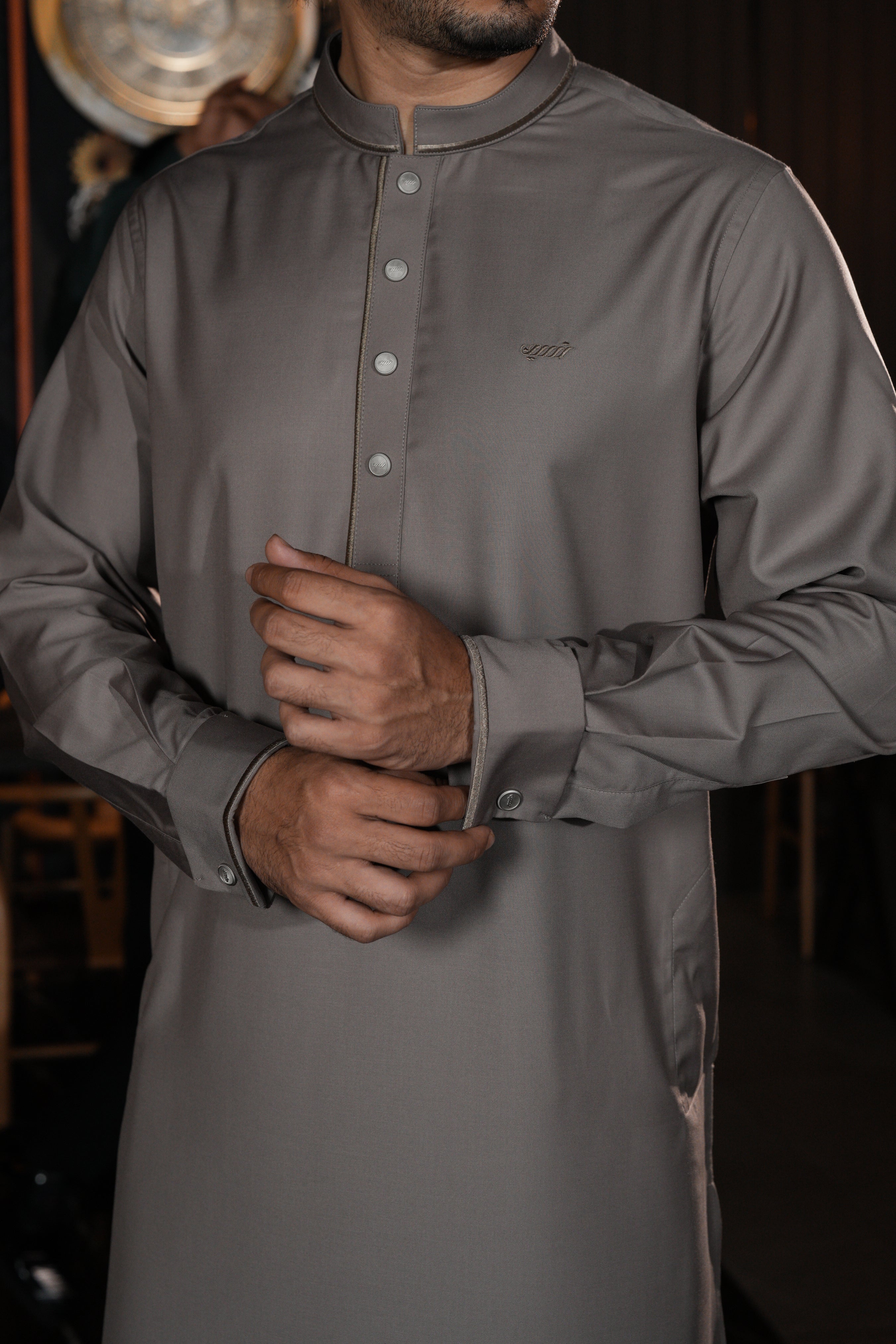 Man wearing a gray traditional outfit with a blurred background