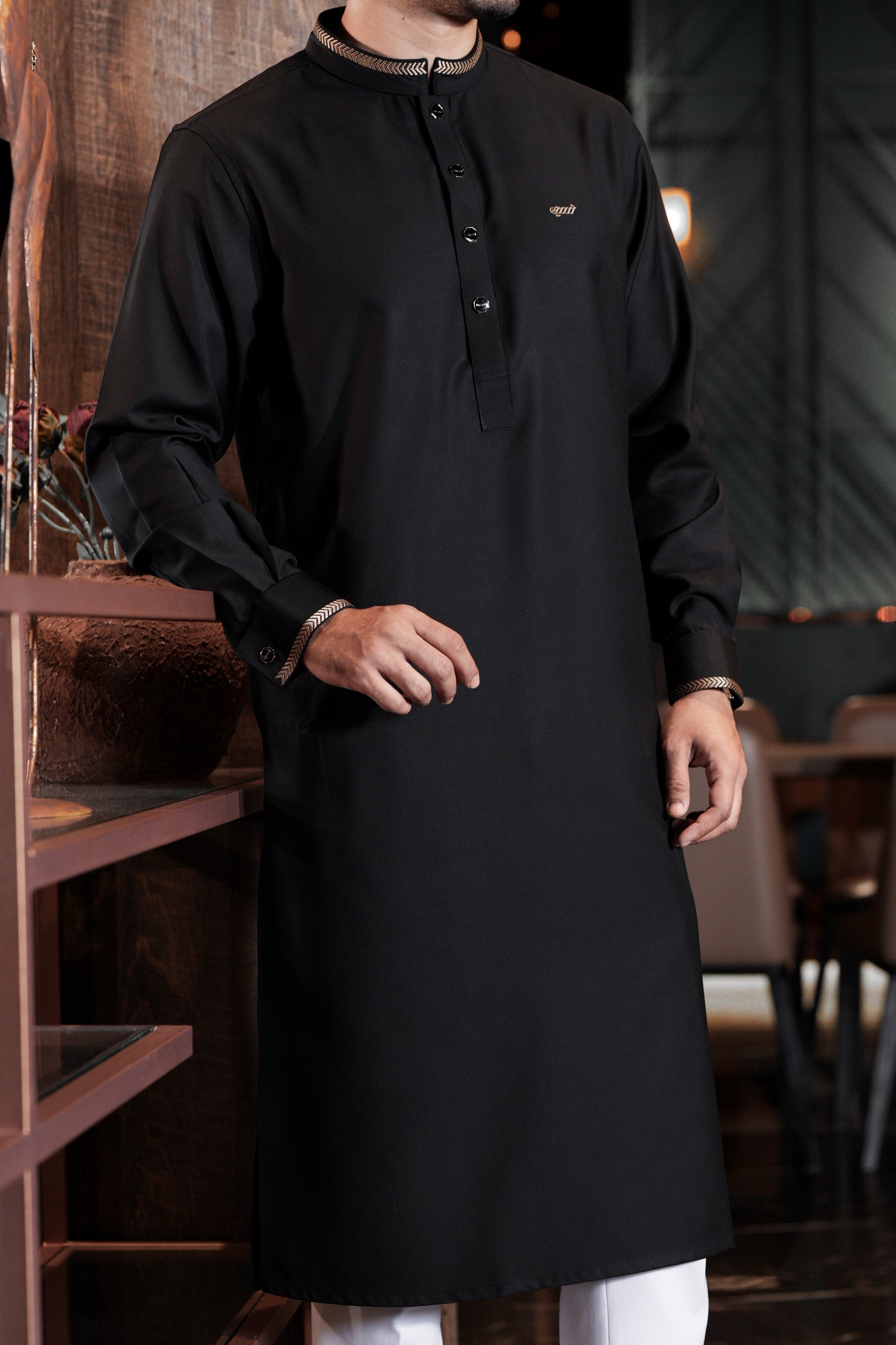 Man wearing a black traditional outfit in an indoor setting