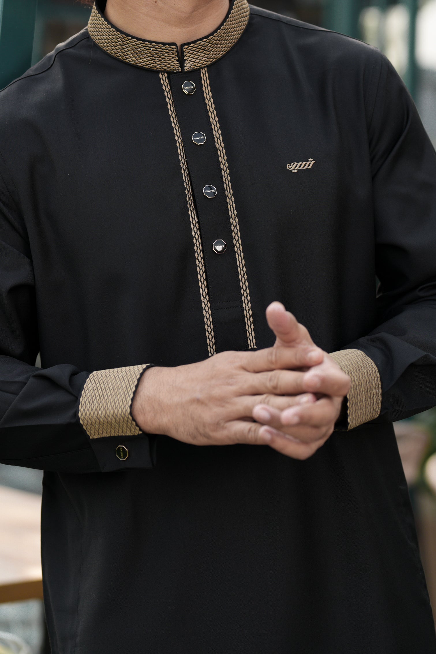 Black traditional outfit with gold embroidery and buttons, featuring a brand logo.