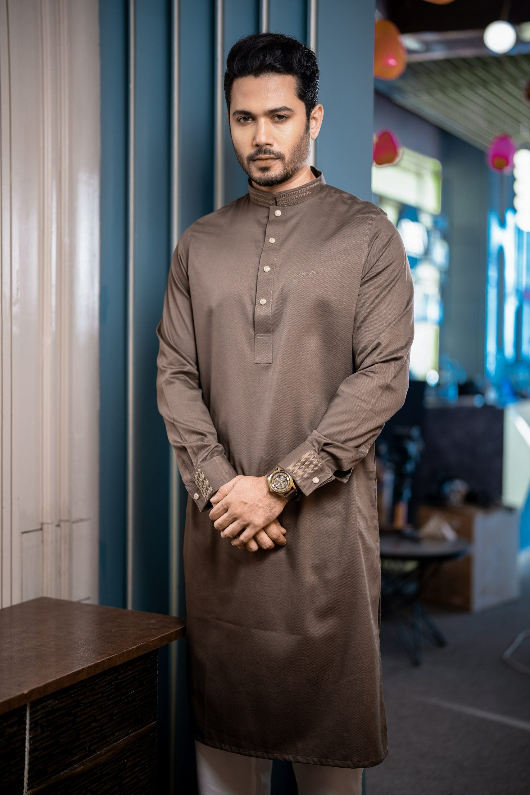 Man wearing a brown traditional outfit in an indoor setting