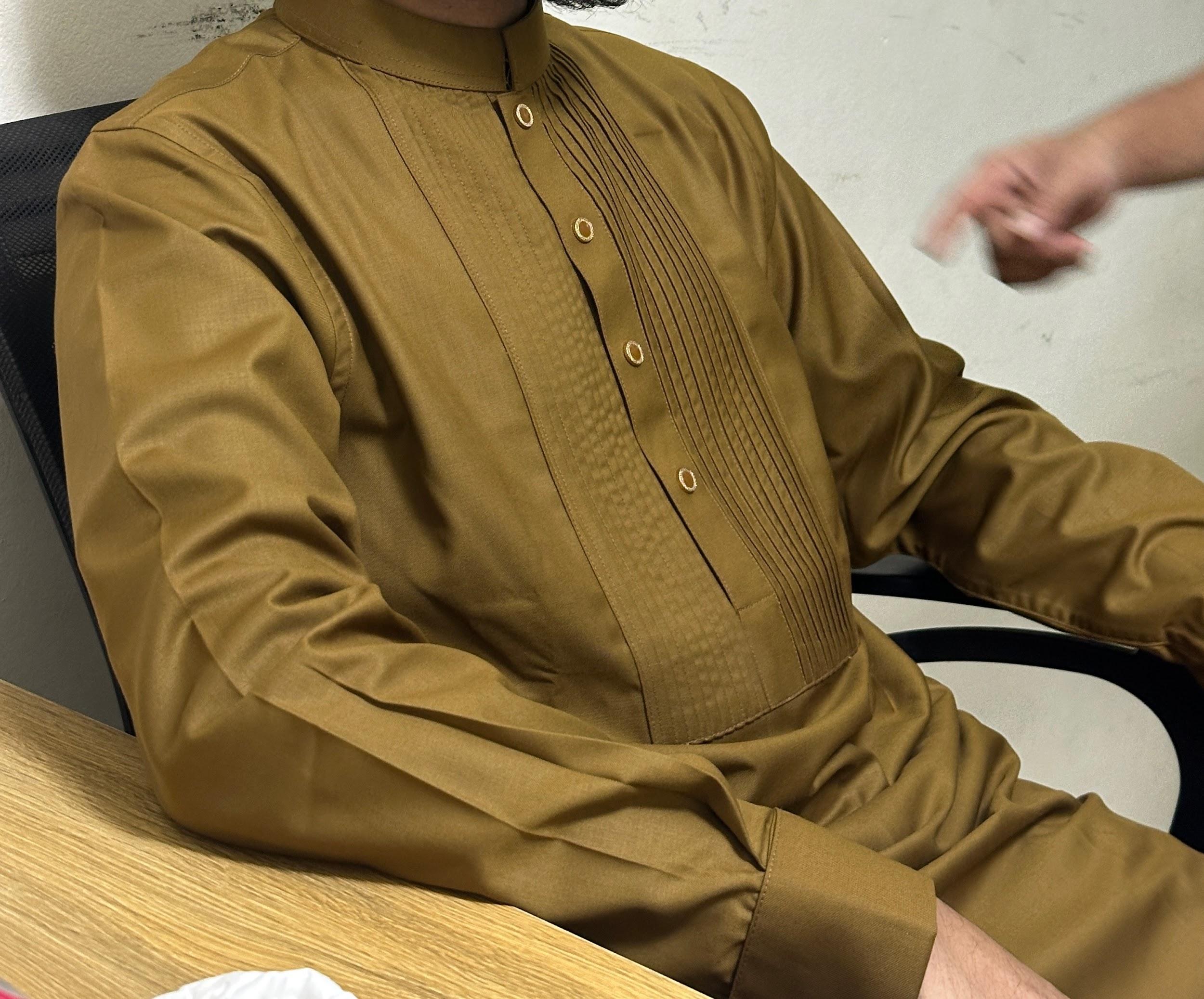 Person wearing a brown traditional outfit sitting at a table.